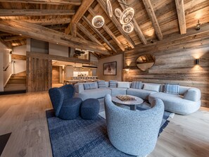 A spacious living room with a large L-shaped sectional sofa, a round coffee table, and a fireplace.