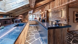 Une cuisine moderne avec un dosseret en pierre, des meubles en bois et un grand îlot central.