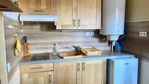 Une cuisine de taille réduite, dotée de meubles en bois, d’une cuisinière encastrée, d’un évier et d’un réfrigérateur.