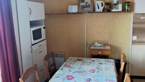 Une petite cuisine équipée d’un four à micro-ondes, d’un petit réfrigérateur, d’une machine à café et d’une étagère sur laquelle sont posés un cadre et une tasse.