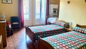Une chambre d’hôtel avec deux lits, un bureau, une chaise, une table à manger et un coin cuisine.