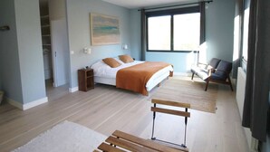 A bedroom with a bed, a chair, a desk, and a wardrobe.