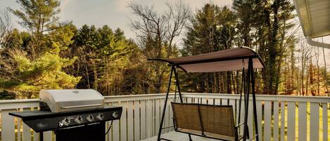 A deck with a barbecue grill and a swing chair.