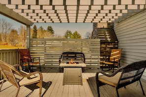 Un patio exterior con una parrilla, sillas de mimbre y vistas del entorno.