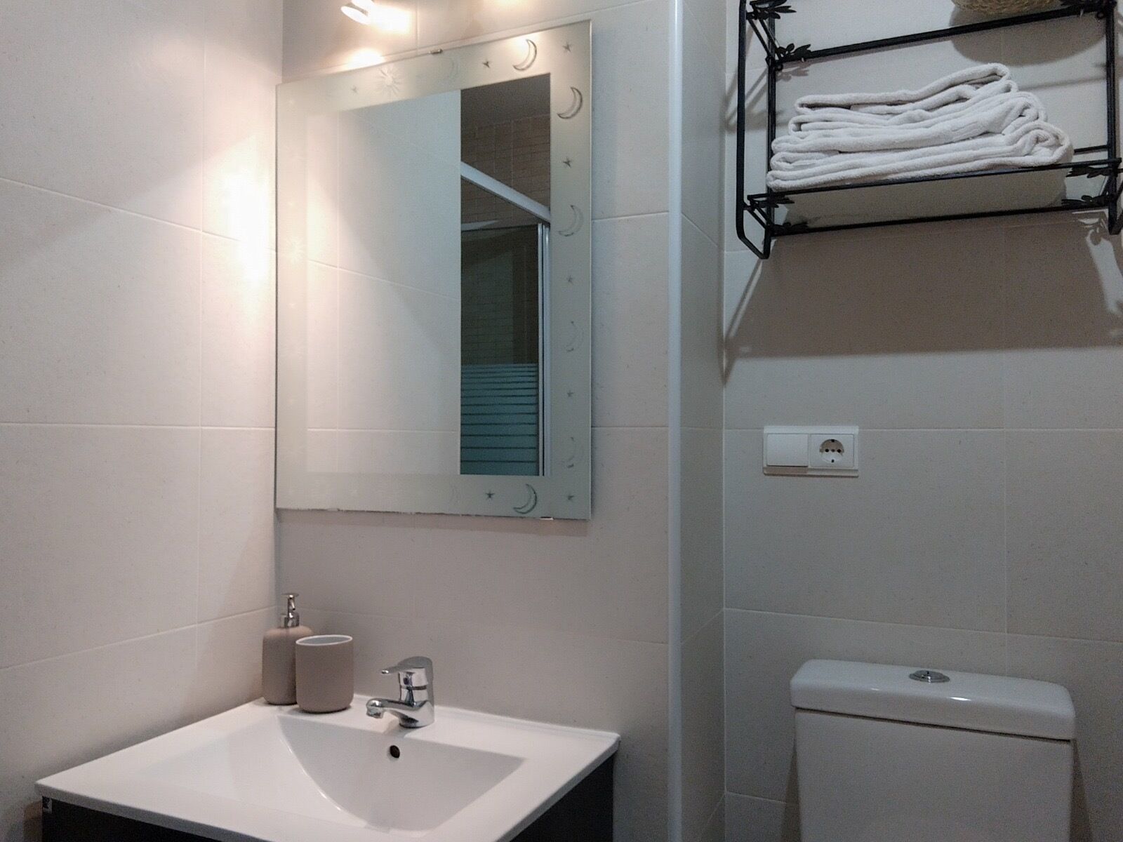 Une salle de bain avec un lavabo blanc, un miroir, un porte-serviettes et des toilettes.