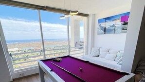 Taula de bitlles en una habitació amb una finestra gran que domina un paisatge urbà.