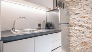 Eine moderne Küche mit Spüle aus Edelstahl, einem Wasserkocher und einer Kaffeemaschine.