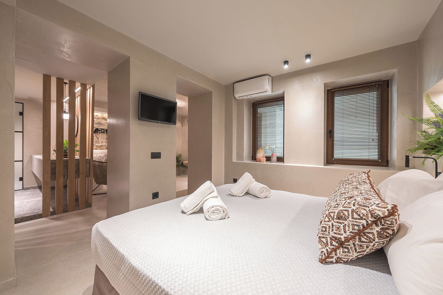 A modern hotel room with a large bed, a TV, air conditioning, and a view of the outside.
