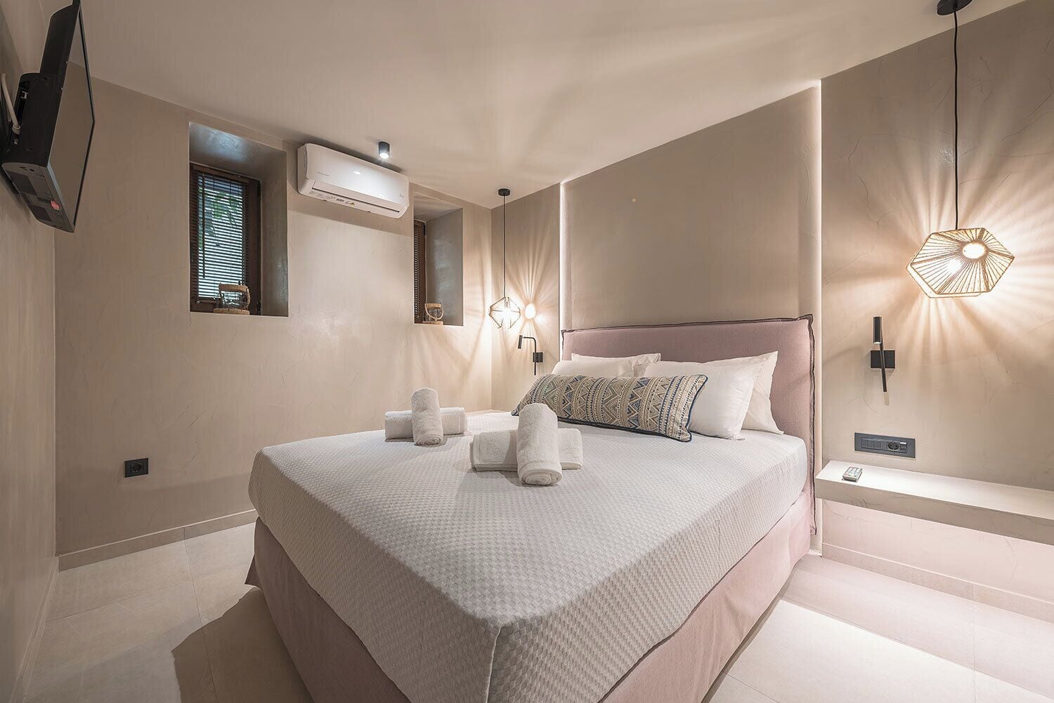 Una camera da letto moderna con un ampio letto, comodini, un condizionatore d'aria e un portalampada a parete.