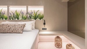 Ein modernes Schlafzimmer mit Bett, Nachttischlampen und einem an der Wand befestigten Fernseher.