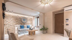 Ein modernes Wohnzimmer mit Steinwand, einem Sofa mit blauen Kissen, einem Holztisch und einer Zimmerpflanze.
