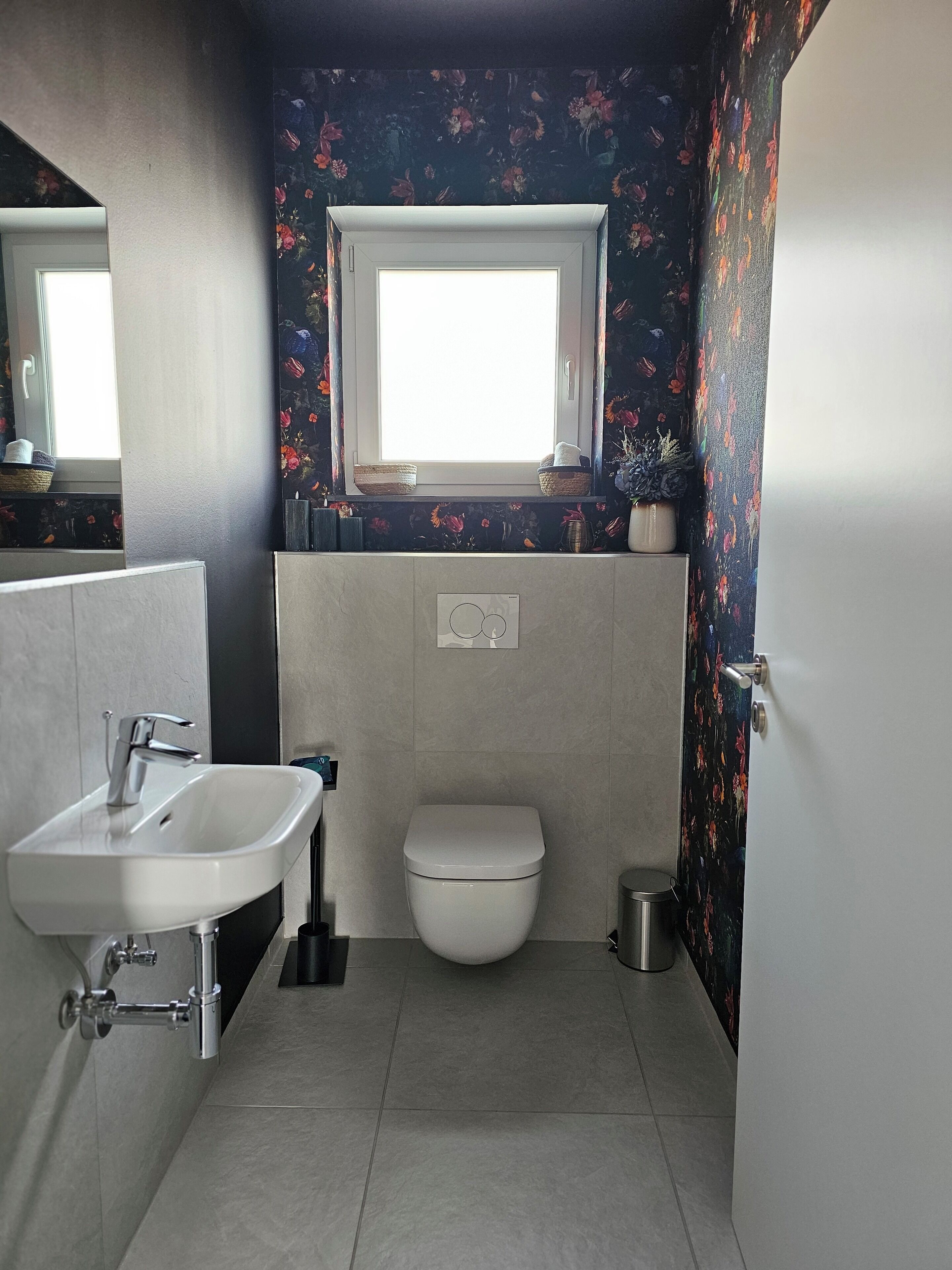 A bathroom with a white sink, toilet, and window.