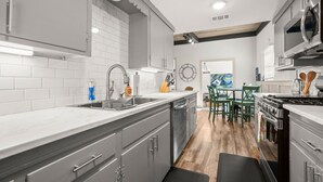Una cocina moderna con baldosas blancas tipo metro, electrodomésticos de acero inoxidable y una zona de comedor de madera.