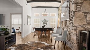 Un salón amplio con chimenea de piedra, una zona de comedor con mesa grande y una acogedora disposición de asientos.
