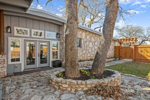 A house with a stone facade, a gray exterior, and a stone planter with two trees. - Exquisite modern retreat 2 blocks from Lake Austin & Nature (Austin)