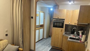 Une petite cuisine équipée avec des meubles en bois, un four encastré et un évier.