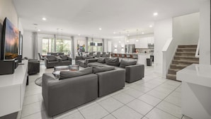 Un salon moderne avec un canapé d’angle, un coin repas et une cuisine en arrière-plan.