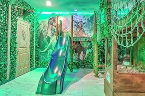 A slide in a room with green foliage and a dinosaur mural. - 2852 Ultimate Retreat for your family 9 Bedrooms! (Kissimmee)