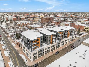 Un edificio de varios pisos con un diseño arquitectónico moderno, que combina espacios comerciales y residenciales.