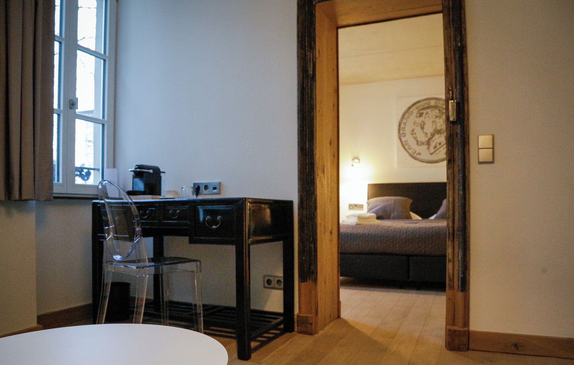A hotel room with a desk, chair, and a bed.