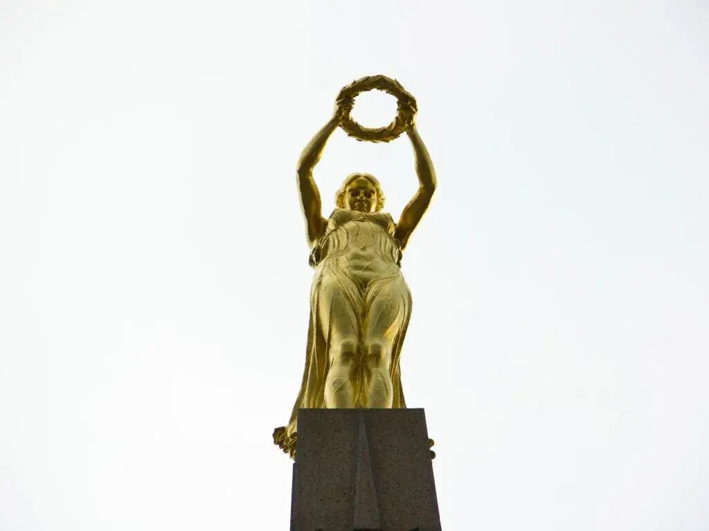 Une statue dorée représentant une femme tenant une couronne de laurier.