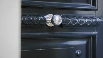 A close-up of a black door with a silver handle and a round keyhole.