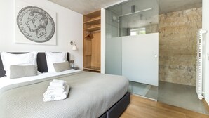 Une chambre à coucher moderne avec un lit, une douche en verre et une armoire en bois.