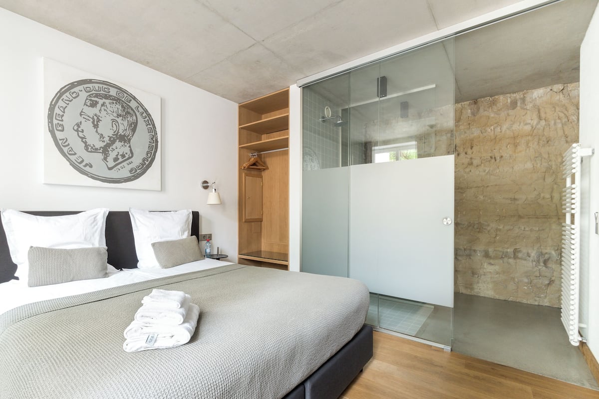 Une chambre à coucher moderne avec un lit, une douche en verre et une armoire en bois.
