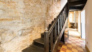 Un escalier avec un mur en pierre d’un côté et un sol à carreaux.