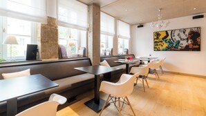 Un espace repas moderne avec un long banc, des tables et des chaises.