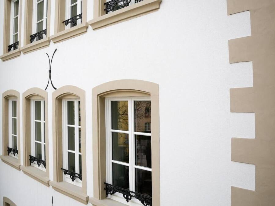 Un edificio con varias ventanas, cada una con marco blanco y pared beige.