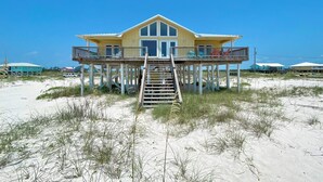 A beachfront house with a wooden deck and a staircase leading to the entrance. - Beautiful Gulf Front Home With Amazing Views! (Gulf Shores)