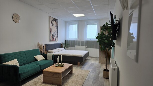 Una camera da letto moderna con un letto, una divisa verde e un tavolino in legno.