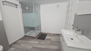 Un bagno con box doccia in vetro, lavandino bianco e WC.