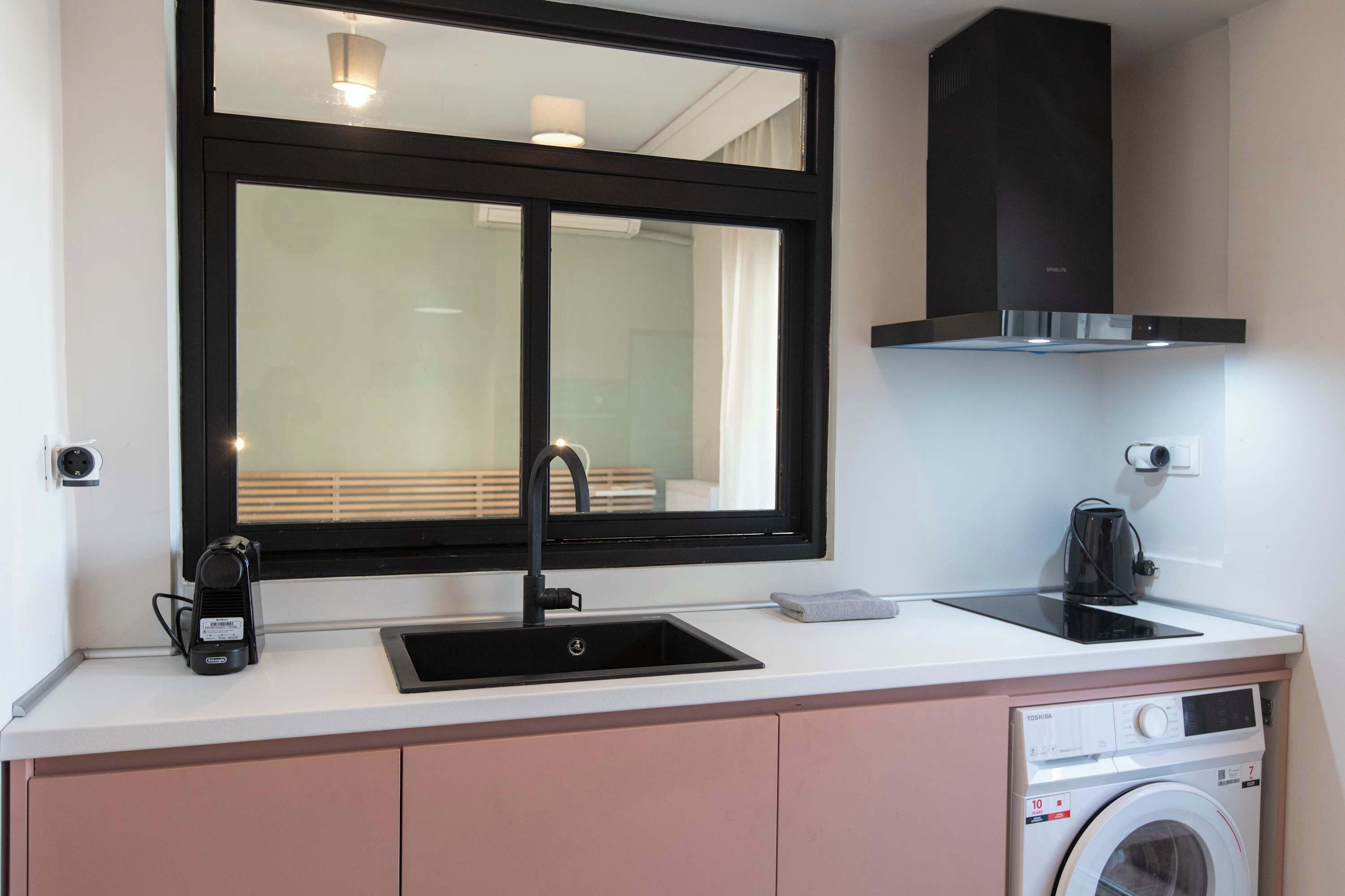 Cocina compacta con lavabo, cafetera, microondas y lavadora integrada.