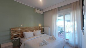 A hotel room with a bed, bedside table, and a view of the outside.