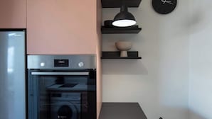 A kitchen with a Bosch oven, a Sharp refrigerator, and a black clock on the wall.