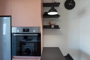 Una cocina con un horno Bosch, un refrigerador Sharp y un reloj negro en la pared.
