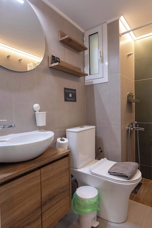 Et moderne badeværelse med et stort spejl, en vask, et toilet og en bruseniche.