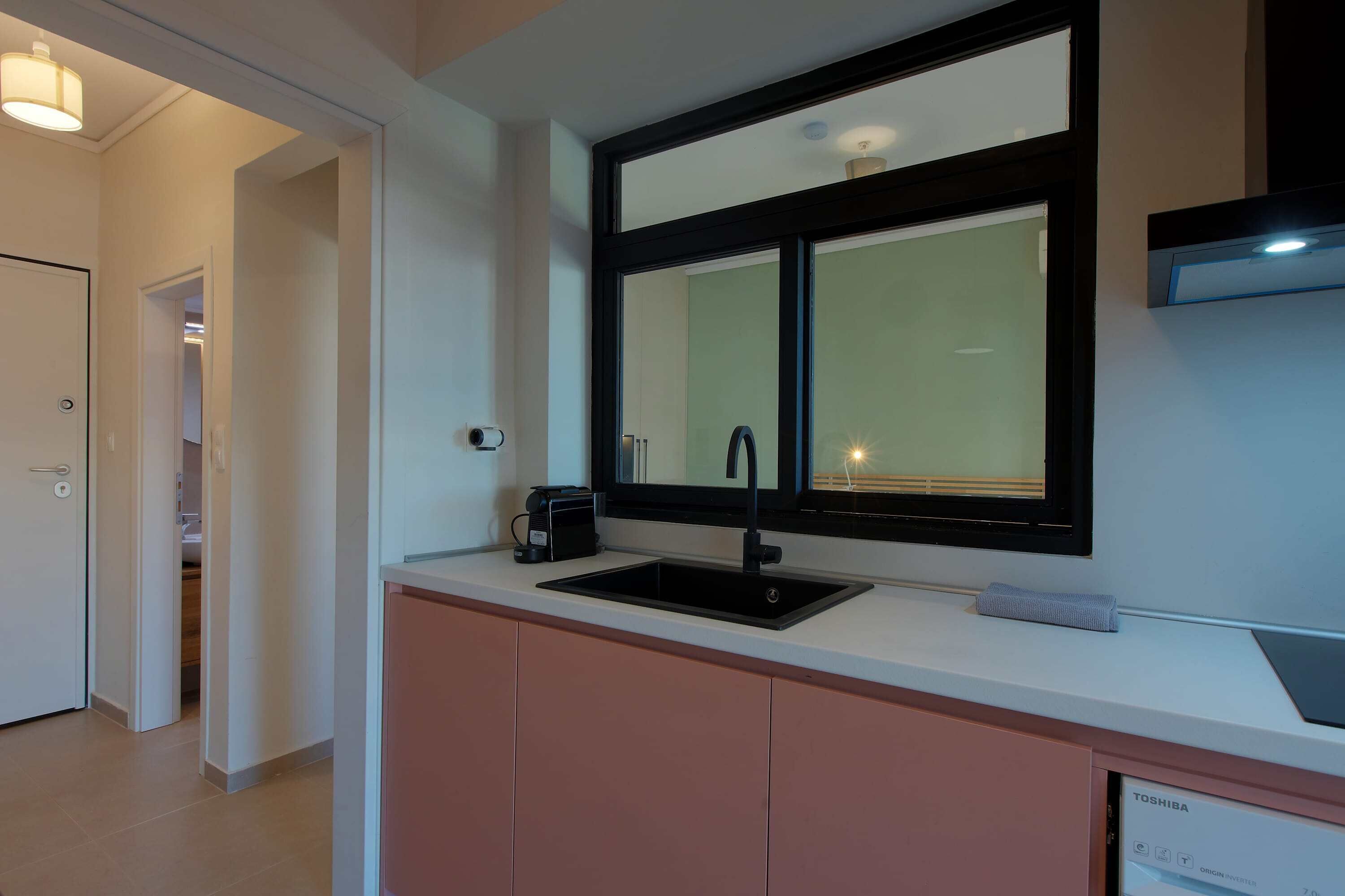 Una cocina moderna con un lavamanos negro, una ventana y un lavavajillas empotrado.