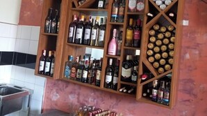 A bar area with multiple shelves of liquor bottles and a countertop with more bottles. - Crux hotel  (Kampala)