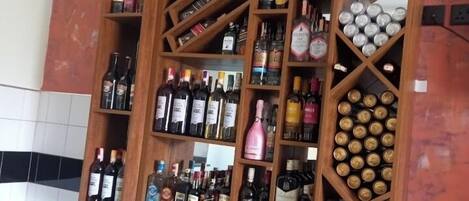 Zona de bar con múltiples estantes llenos de botellas de licores y una barra con más botellas.