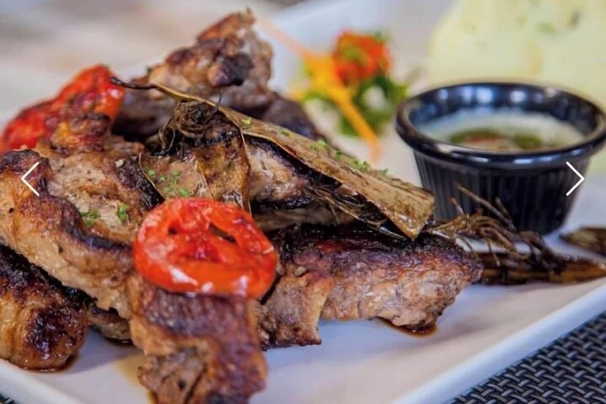 Grilled meat with a side of vegetables and a dipping sauce.