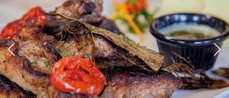 Grilled meat with a side of vegetables and a dipping sauce.