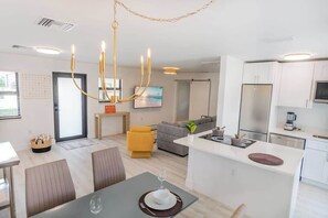 Una cocina moderna con armarios blancos, un refrigerador de acero inoxidable y un microondas integrado.
