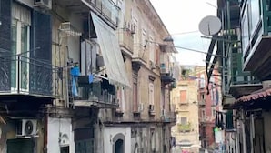 A narrow street lined with multi-story buildings, some with balconies and satellite dishes. - Guazzo Home b&b Rione Sanità  (Napoli)