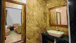 A bathroom with a large mirror, a sink, and a marble wall. - Gulmohar Retreat And Spa (Kumbhalgarh)