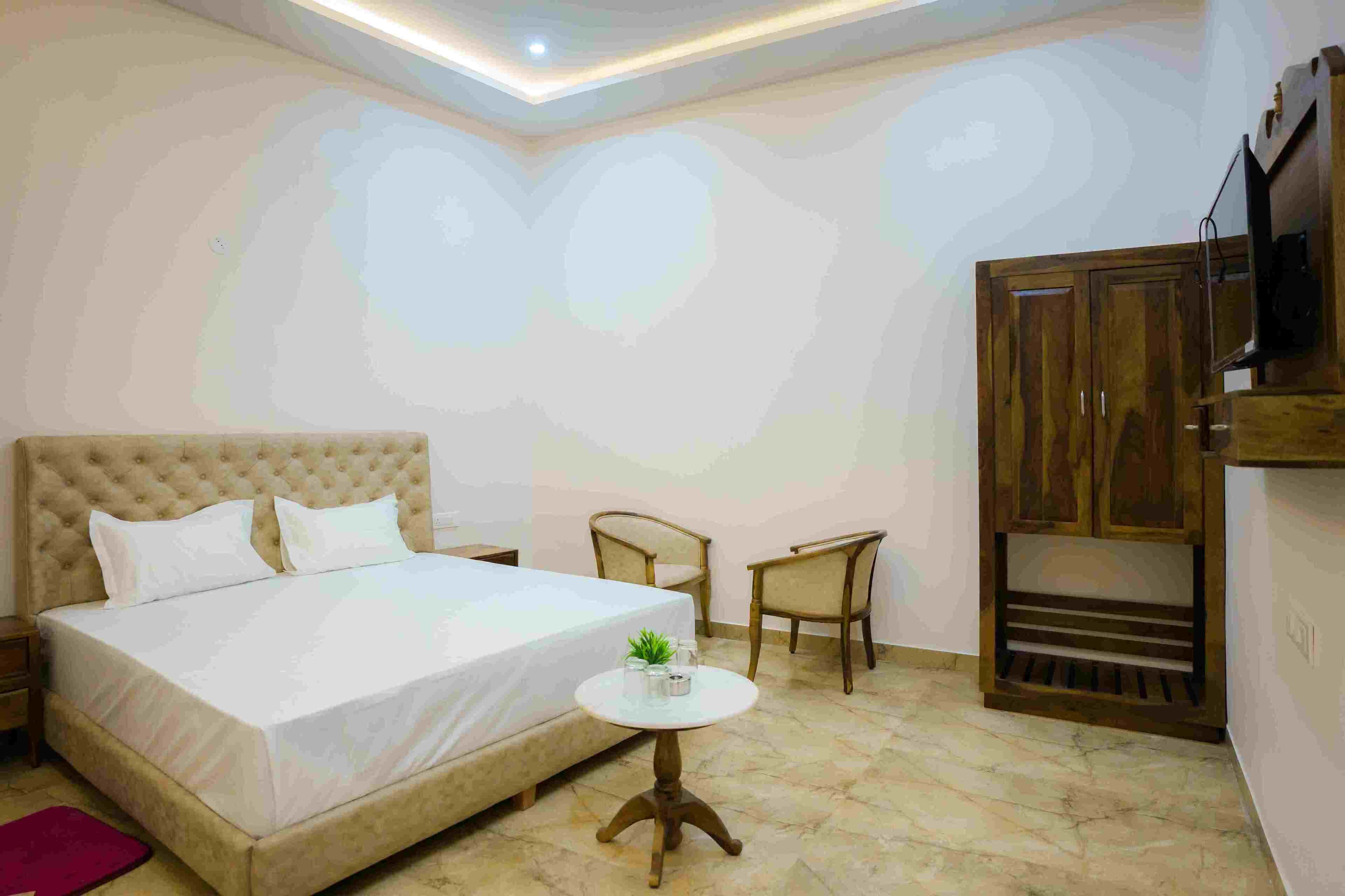 Une chambre à coucher avec un grand lit, deux chaises, une petite table et une armoire.