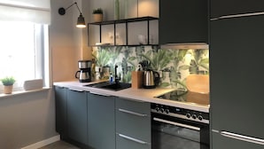 Una cucina moderna con mobili scuri, forno integrato, macchina del caffè e ripiano con bicchieri.