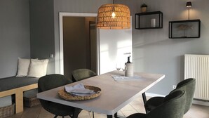 Un'elegante sala da pranzo con tavolo, sedie, lampadario e un'ornamento a forma di pesce appeso alla parete.